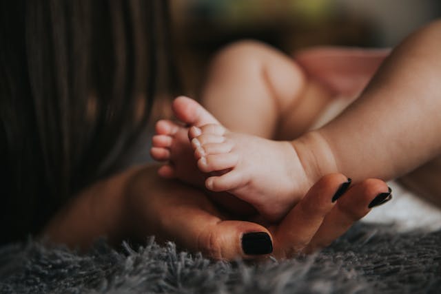 mother's hand holding baby's foot tenderly